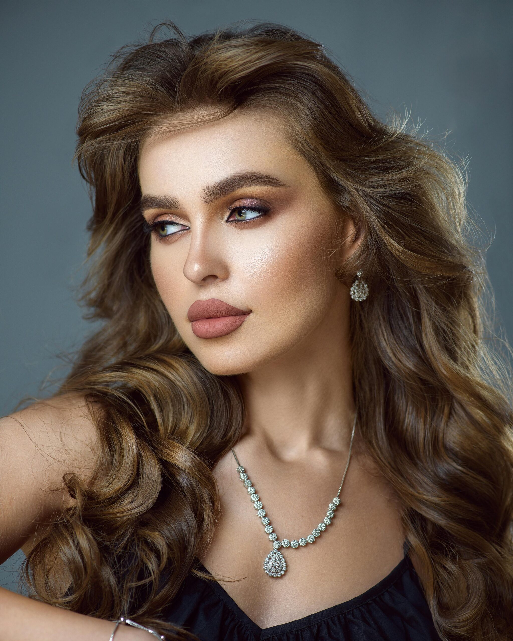 Stylish portrait of an elegant woman with luxurious diamond jewelry and wavy hair.