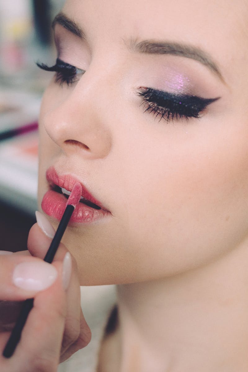 Close-up of an elegant woman having makeup applied, highlighting fashion and beauty.